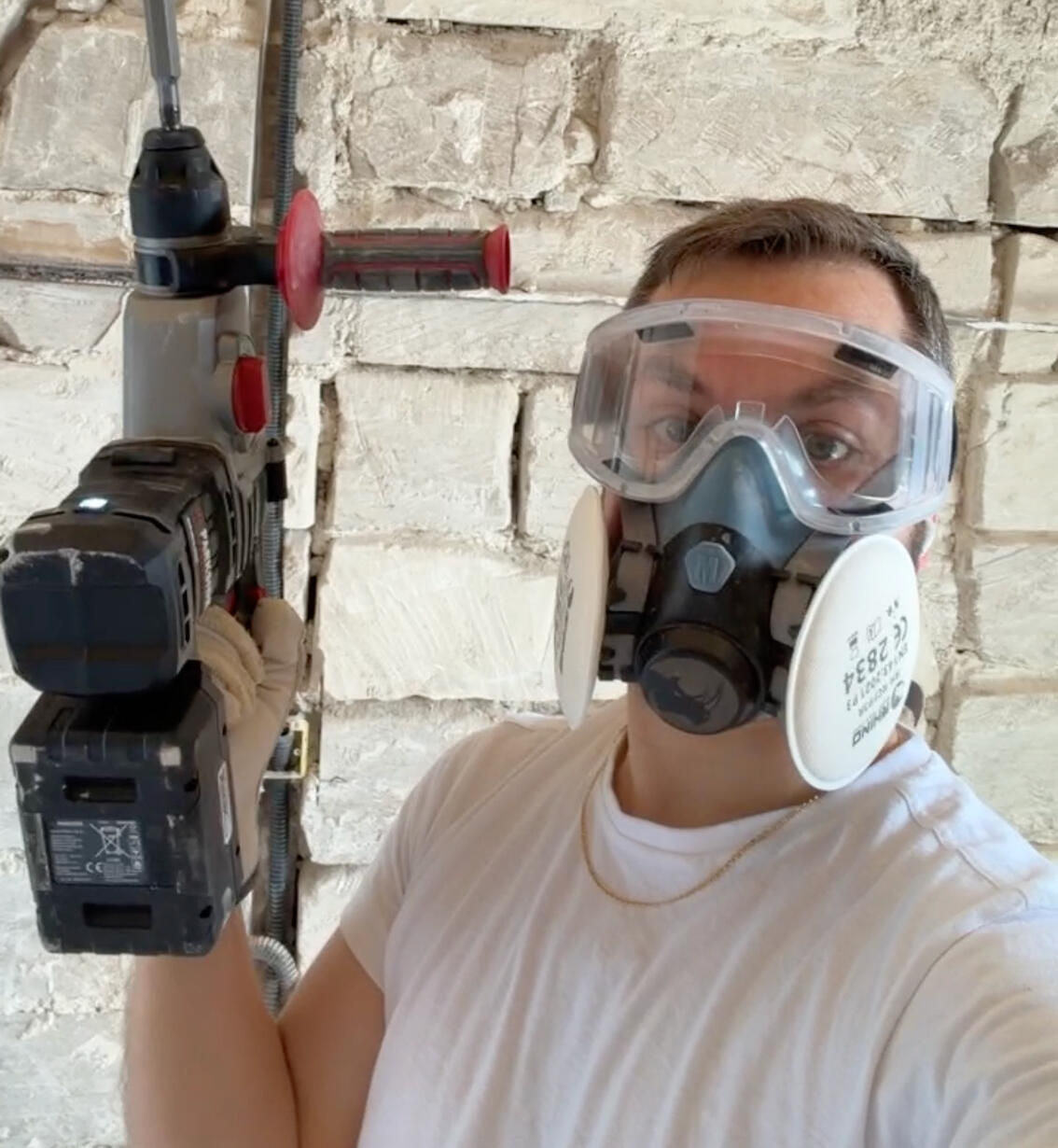 Roma building Roma is holding an electrical hammer and wearing protection googles and mask